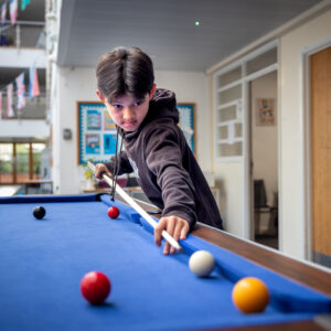 Young boarding boy playing pool