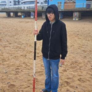 student with measuring stick on Ramsgate Beach
