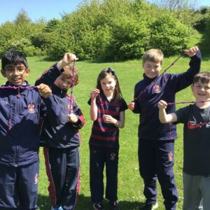 Year 4 children standing in a field learning to knot ropes