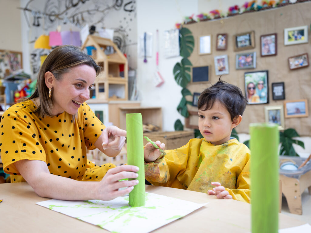 Nursery teacher and child building blocks