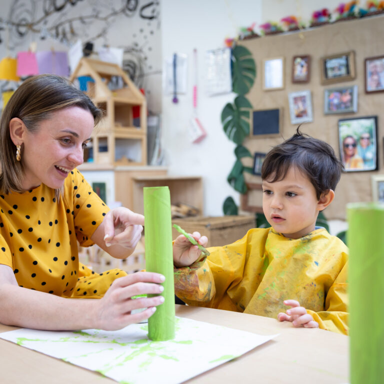Nursery teacher and child building blocks