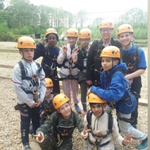 Girls and boys ready for abseiling in orange helmets with teacher