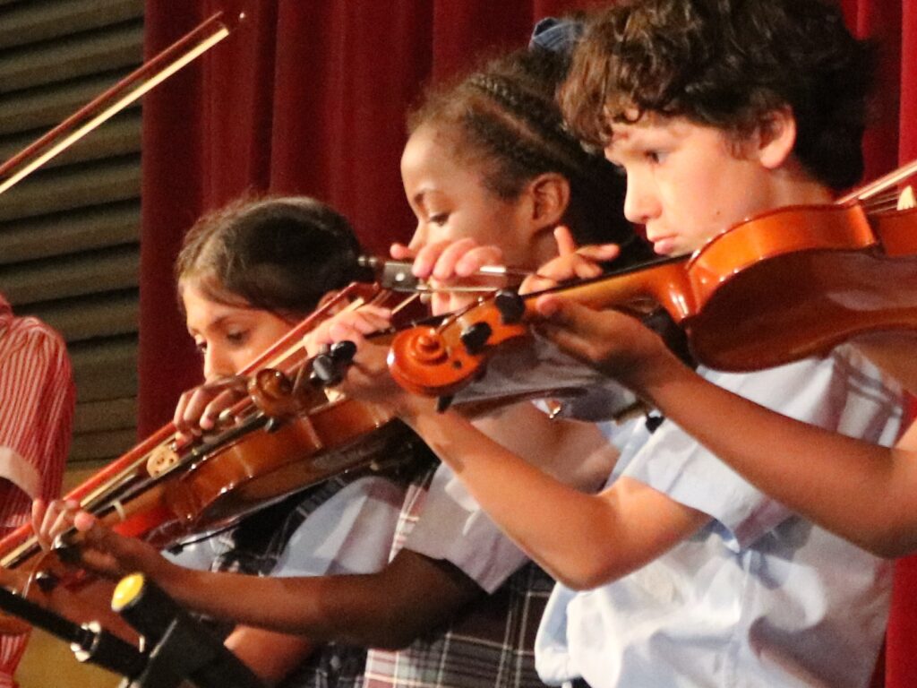 Three children playing violins