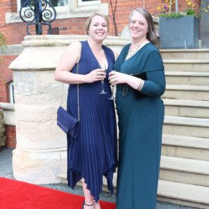 Two ladies holding glasses on red carpet