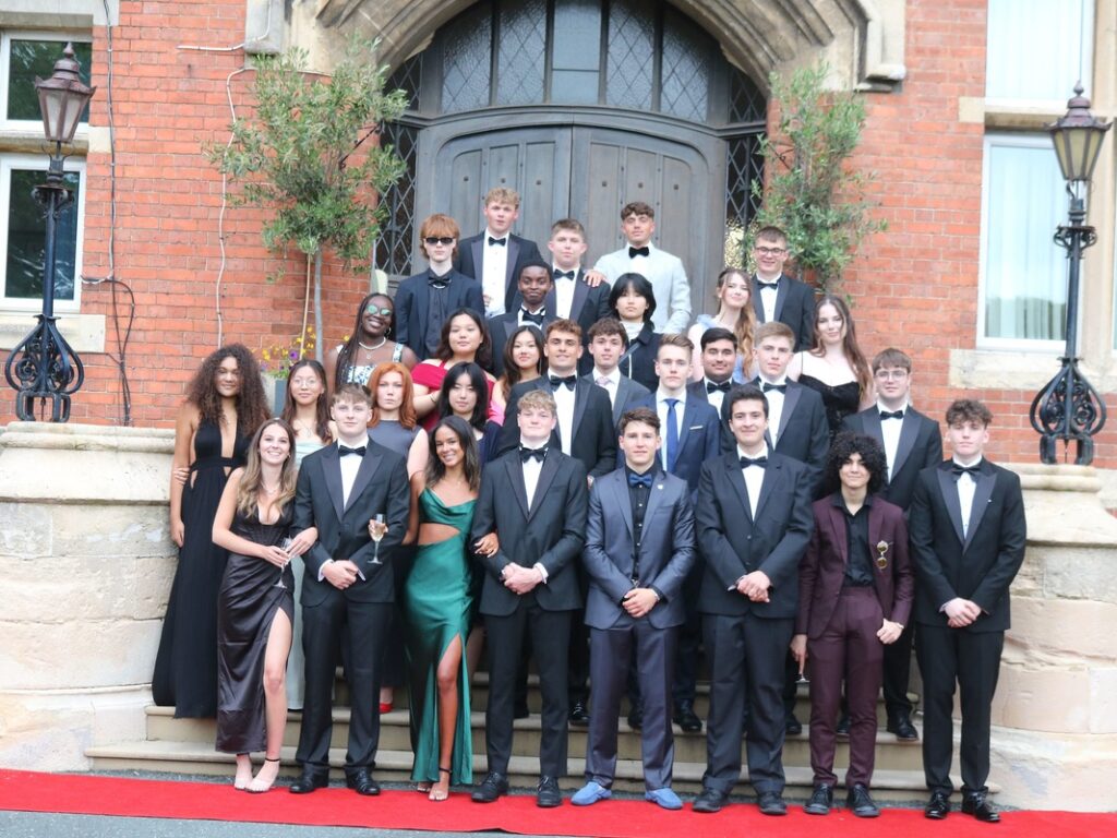 Group of students standing outside red brick school for black tie event