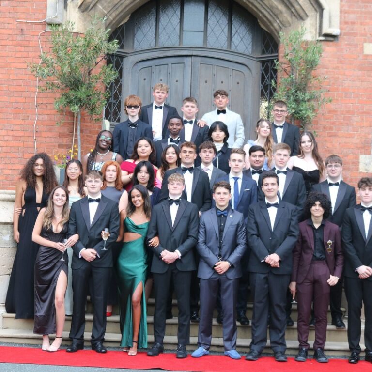 Group of students standing outside red brick school for black tie event