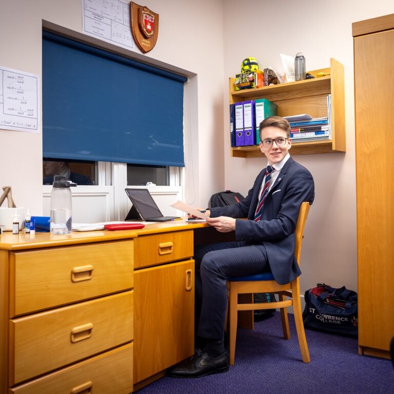 Boy sat at a desk in boarding bedroom