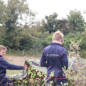 two school boys putting up camouflage tent