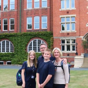 Family smiling in front of school