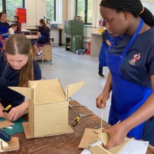 Two girls cutting cardboard