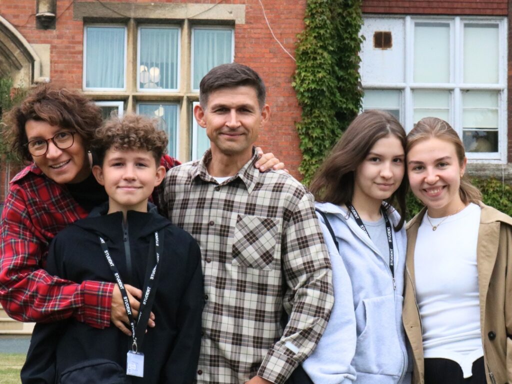 Family smiling in front of building