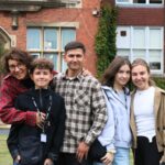 Family smiling in front of building